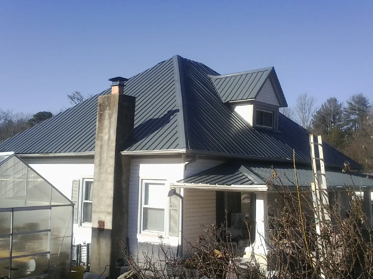 Dark blue standing seam metal roof on a white farmhouse with dormer — Slate & Tile Roof Repair by Roofing Brothers in Mountlake Terrace