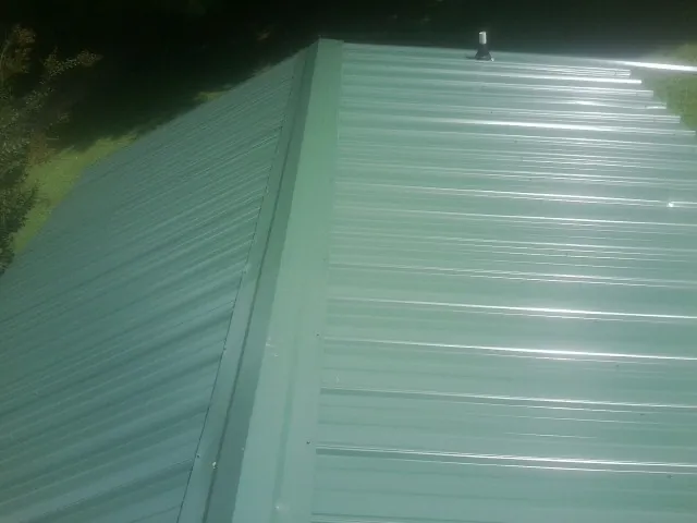 New green metal panels meeting at the ridge of a roof — Flat Roof Repair work by our crew in Mountlake Terrace