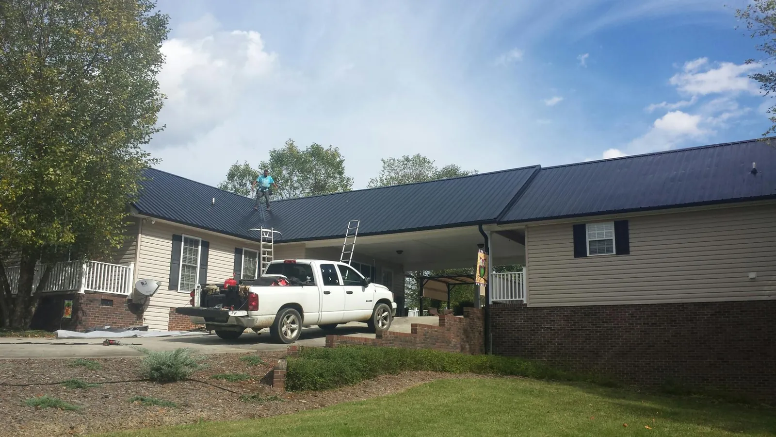 Black metal roof over a home and attached breezeway with ladders set in Mountlake Terrace