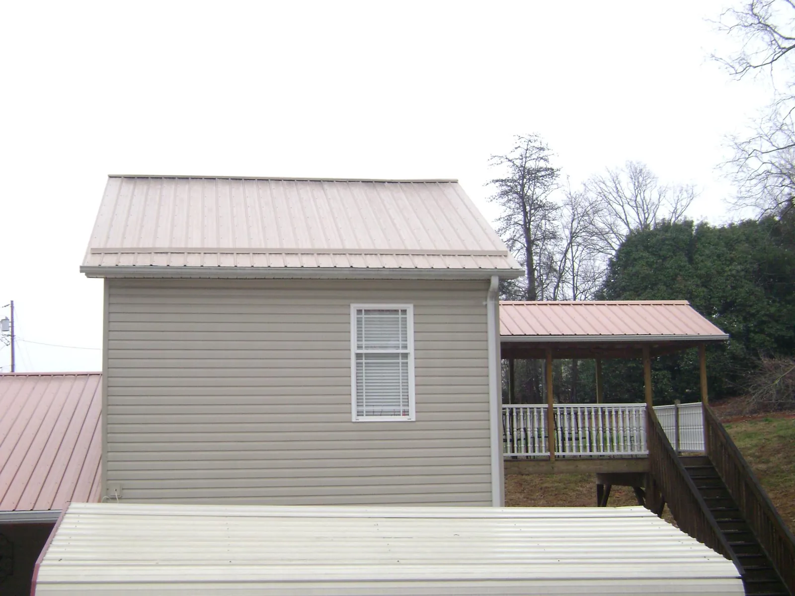 Tan metal roofs on a two story addition and attached porch, from a Roof Replacement job in Mountlake Terrace