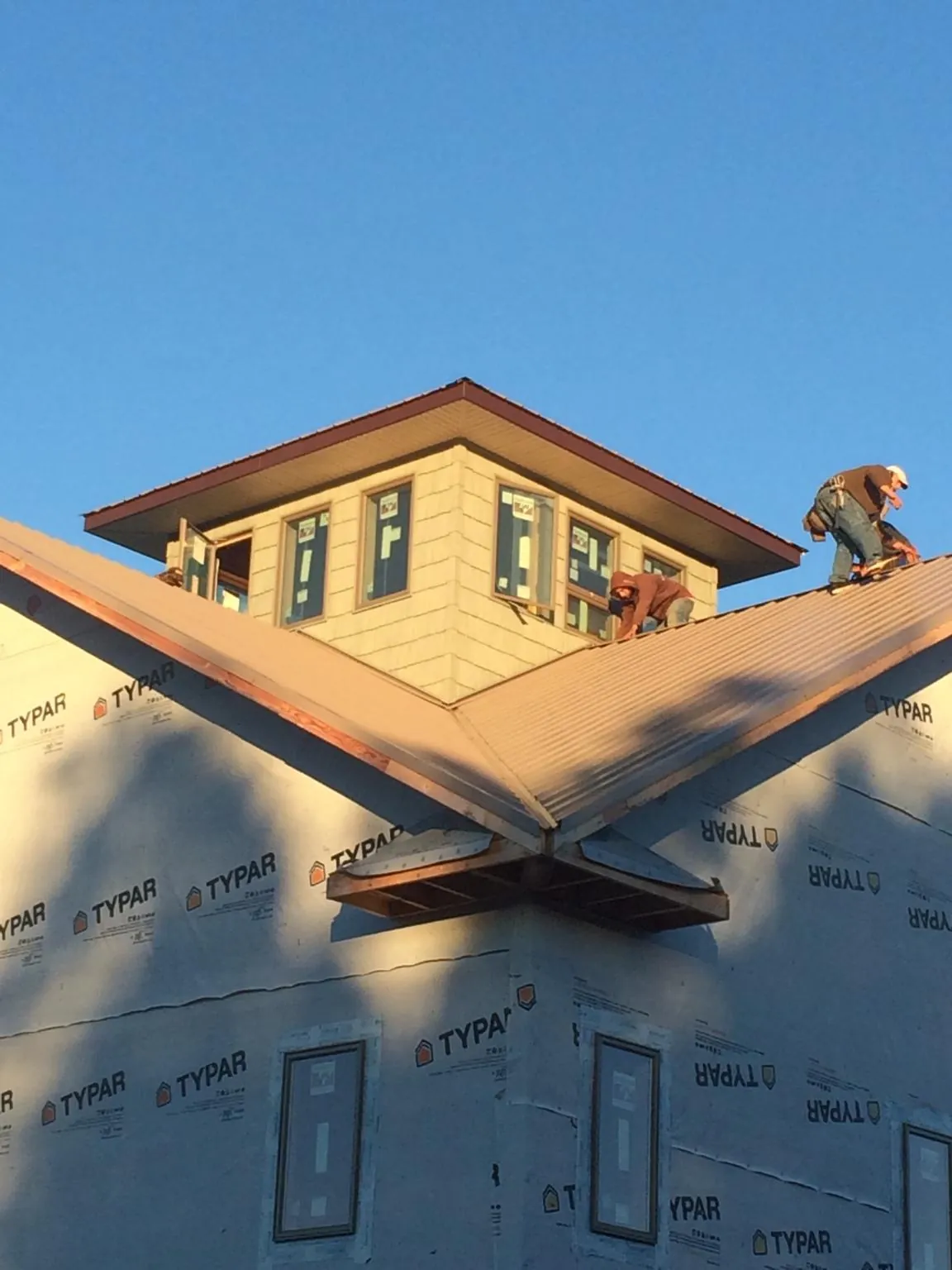Roofers working around a rooftop cupola on a new metal roof at sunset — Roof Waterproofing in Mountlake Terrace by Roofing Brothers